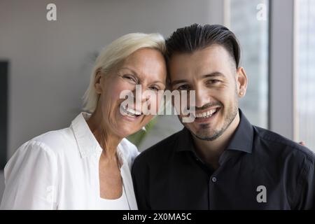 Eine fröhliche ältere Frau und ein junger erwachsener Sohn posierten drinnen Stockfoto