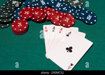 Vier von einer Art von vier Assen und eine Bank von Chips auf dem Hintergrund des grünen Tisches im Casino beim Poker Stockfoto