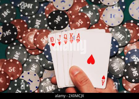 Royal Flush in den Händen des Spielers auf dem Hintergrund von Spielchips. Eine Kombination von Karten im Poker aus nächster Nähe gewinnen Stockfoto