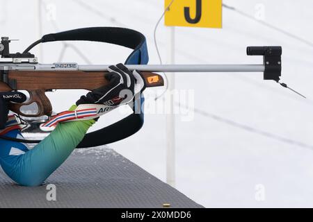 Sportlerbiathletin-Gewehrschießen in Bauchlage. Selektiver Fokus, extreme Nahaufnahme. Biathlet im Schießstand des offenen Jugendbiathlon-Wettkampfes Stockfoto