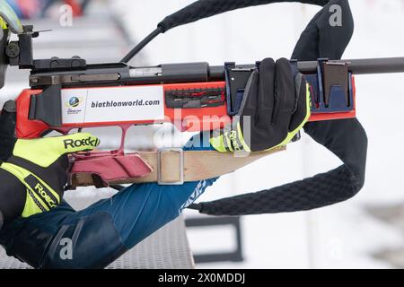 Sportlerbiathletin-Gewehrschießen in Bauchlage. Selektiver Fokus, extreme Nahaufnahme. Biathlet im Schießbereich. Offener Jugendbiathlon-Wettkampf Stockfoto