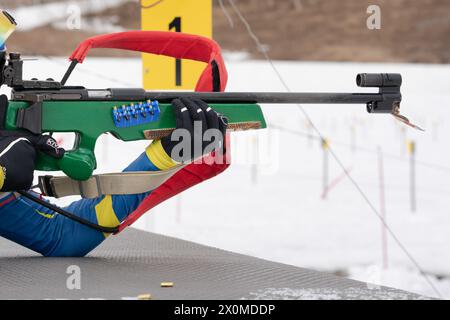 Sportlerbiathletin-Gewehrschießen in Bauchlage. Selektiver Fokus, extreme Nahaufnahme. Biathlet im Schießbereich. Offener Jugendbiathlon-Wettkampf Stockfoto