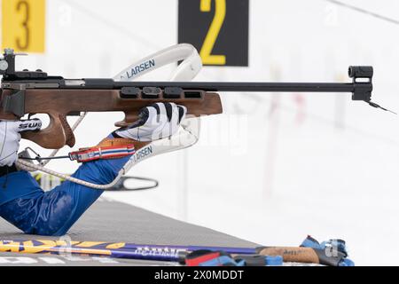 Sportlerbiathletin-Gewehrschießen in Bauchlage. Selektiver Fokus, extreme Nahaufnahme. Biathlet im Schießstand. Junior-Biathlon-Wettkampf Stockfoto