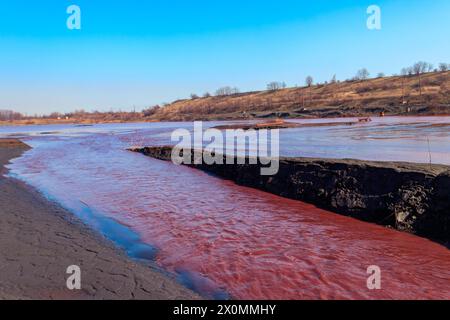 Technischer Siedler von Industriewasser der Bergbauindustrie in Kryvyi Rih, Ukraine. Rotes Wasser verschmutzt mit Eisenerzabfällen. Ableitung von Prozesswasser in Stockfoto