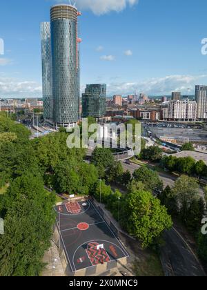 Luftaufnahme des Basketballplatzes Hulme Park in Manchester, Großbritannien mit Wolkenkratzern dahinter Stockfoto