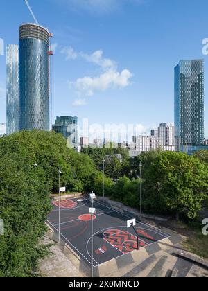 Luftaufnahme des Basketballplatzes Hulme Park in Manchester, Großbritannien mit Wolkenkratzern dahinter Stockfoto