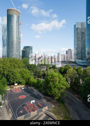 Luftaufnahme des Basketballplatzes Hulme Park in Manchester, Großbritannien mit Wolkenkratzern dahinter Stockfoto