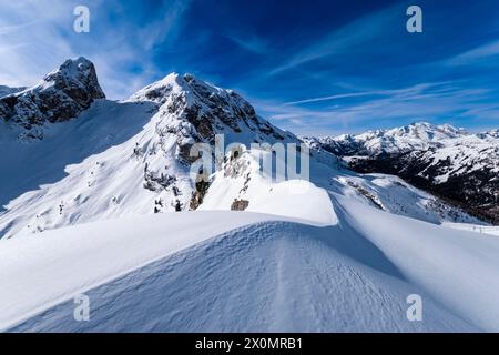 Schneetreiben schafft kunstvolle Strukturen rund um den Giau Pass im Winter, schneebedeckte Gipfel des Torre Dusso, Mt. Cernera und Marmolada in der Ferne. Stockfoto