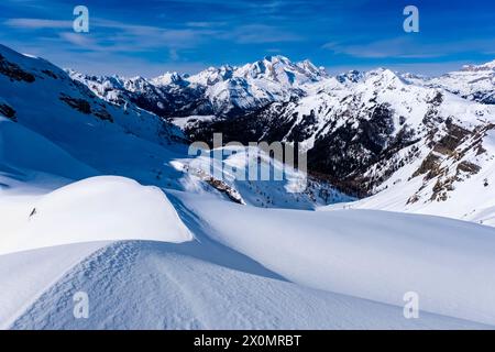 Schneetreiben schafft kunstvolle Strukturen rund um den Giau Pass im Winter, alpine Dolomitenlandschaft und schneebedeckte Gipfel der Marmolada Gruppe in der Ferne Stockfoto