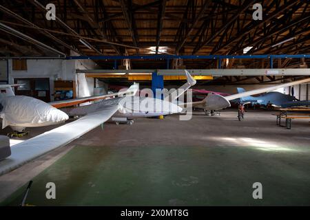 Flugplatz Ansbach Petersdorf, Deutschland. April 2024. Überdachte Segelflugzeuge parken im Hangar eines Clubs. Quelle: Pia Bayer/dpa/Alamy Live News Stockfoto