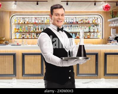 Kellner mit einem Tablett mit Rotwein und Gläsern in einer Bar Stockfoto