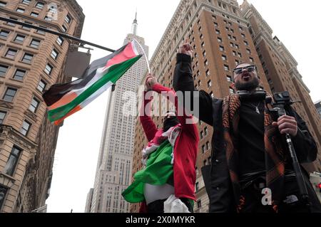 Pro-palästinensische Demonstranten schwingen eine palästinensische Flagge und singen Slogans auf dem Herald Square mit dem Empire State Building im Hintergrund. Pro-palästinensische Demonstranten versammelten sich in Manhattan, New York City, um die Militäroperationen der israelischen Streitkräfte in Gaza zu verurteilen. Beamte des Weißen Hauses sagten, sie kommunizieren mit israelischen Beamten, um sich auf einen möglichen Vergeltungsschlag des Iran gegen Israel vorzubereiten. Die mögliche Vergeltungsmaßnahme könnte als Reaktion auf einen israelischen Luftangriff erfolgen, bei dem mehrere führende iranische Militärkommandanten in Syrien am 1. April getötet wurden. Seit Beginn des Krieges am 7. Oktober Stockfoto