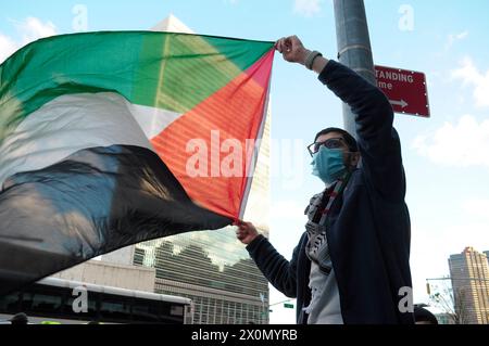 Ein pro-palästinensischer Demonstrant schwingt eine palästinensische Flagge vor dem Gebäude der Vereinten Nationen. Pro-palästinensische Demonstranten versammelten sich in Manhattan, New York City, um die Militäroperationen der israelischen Streitkräfte in Gaza zu verurteilen. Beamte des Weißen Hauses sagten, sie kommunizieren mit israelischen Beamten, um sich auf einen möglichen Vergeltungsschlag des Iran gegen Israel vorzubereiten. Die mögliche Vergeltungsmaßnahme könnte als Reaktion auf einen israelischen Luftangriff erfolgen, bei dem mehrere führende iranische Militärkommandanten in Syrien am 1. April getötet wurden. Seit Beginn des Krieges am 7. Oktober 2023 sagte das gesundheitsministerium von Gaza mehr als Stockfoto