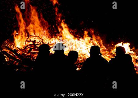 Osnabrück, Deutschland 31. März 2024 im Bild: Zu Ostern werden als Brauch die Osterfeuer entzündet. Flammen und Rauch in den Himmel. Die Gäste als Silhouette schauen sich das Feuer an. Niedersachsen *** Osnabrück, Deutschland 31. März 2024 im Bild zu Ostern werden Osterbrände vielerorts Brauch entzündet, Flammen und Rauch schweben in den Himmel die Gäste in Silhouette beobachten das Feuer Niedersachsen Copyright: XFotostandx/xReissx Stockfoto