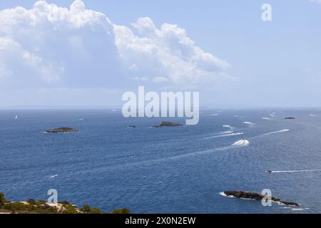 Blick auf das Mittelmeer, während Freizeit- und Schnellboote vom Hafen Eivissa auf Ibiza abfahren und ein Gitter aus weißen Wachen mit kleinen Inseln hinterlassen Stockfoto