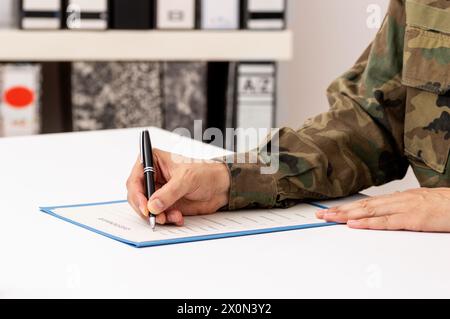 Nahaufnahme einer Hand eines Militärs, der ein Dokument auf einem Schreibtisch in der Militärakademie schreibt oder unterschreibt Stockfoto
