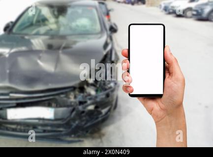 Hand mit einem leeren Bildschirm Telefon mit einem Autounfall im Hintergrund Stockfoto