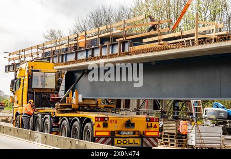 Owschlag, Deutschland. April 2024. Auf einer Baustelle an der Autobahn A7 zwischen den Anschlussstellen Owschlag und Rendsburg/Büdelsdorf werden vorgefertigte Brückenbauteile in Position gebracht. Die Fahrbahn in Richtung Hamburg wird vom 12. April 2024 von 20 Uhr bis 15. April 2024 um 5 Uhr gesperrt. Die Träger werden zunächst auf Tiefladern auf die Baustelle geliefert und dann mit einem 500-Tonnen-Kran in Position gebracht. Quelle: Axel Heimken/dpa/Alamy Live News Stockfoto