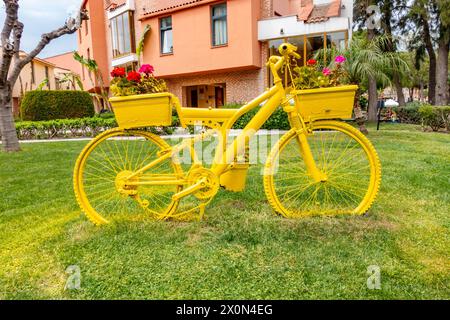 Ein altes Fahrrad, das mit Sprühfarbe umfunktioniert wurde, um es in einen dekorativen, farbenfrohen Gartentopf zu verwandeln Stockfoto