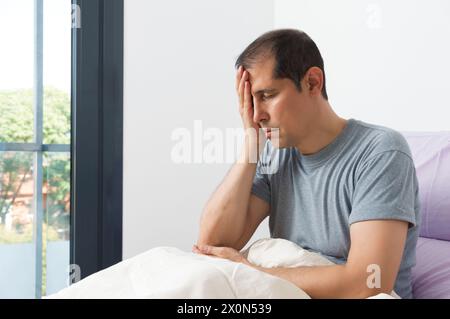 Aufnahme eines jungen Mannes, der an Migräne litt und sich in seinem Schlafzimmer beschwerte Stockfoto