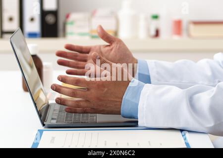Männlicher Hausarzt, der Videokonferenzen auf einem Laptop mit Hilfe einer Online-Video-Anruf-Beratungs-App führt. Medizinische Fernhilfe für Fernversorgung Stockfoto