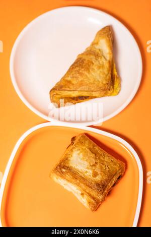 Zwei Stücke vegetarischer Blätterteig auf einem Teller auf orangefarbenem Hintergrund. Stockfoto