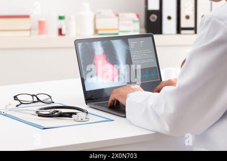 Freigestellte Aufnahme eines Kardiologen, der mit einem Laptop in der Praxis arbeitet. Gesundheitskonzept Stockfoto