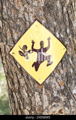 Ein gelbes Schlangenwarnschild auf einem Kiefernstamm auf der Insel Ibiza, Balearen, Spanien Stockfoto