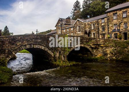 Die zweibogige Steinbrücke überquert den Fluss Colwyn in der kleinen malerischen Stadt Beddgelert im Eryri National Park, Wales Stockfoto