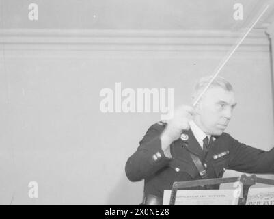 DER 14-JÄHRIGE JUNGE IST MITGLIED DER ROYAL MARINES BAND. 8. JANUAR 1942, SCARBOROUGH. DER 14-JÄHRIGE REGINALD DAVID WARDEN TRAT DER ROYAL MARINE SCHOOL OF MUSIC IN SCARBOROUGH BEI UND WURDE IHR JÜNGSTES MITGLIED. DIE SCHULE VERSORGT ALLE MUSIKER UND MARINEBANDS MIT HM-SCHIFFEN UND LANDBASEN. - Der Bandmaster geht durch die Bandparts, zum Wohle der Jugendlichen in der ersten Stunde Stockfoto