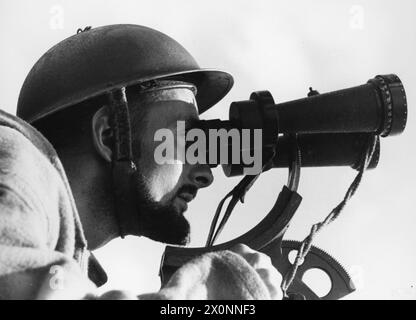 Ein BESUCH AUF EINEM FLUGABWEHRSCHIFF, ENGLAND, 1940 - Ein eindrucksvolles Porträt des Profils eines Anti-Aircraft Control Spotter, der vom Deck dieses Flugabwehrschiffs aus durch ein Fernglas blickt, irgendwo in England, 1940 Stockfoto