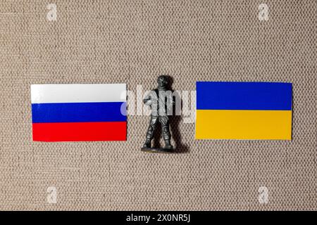 Die Figur eines Soldaten auf dem Hintergrund der Fahnen Russlands und der Ukraine Stockfoto