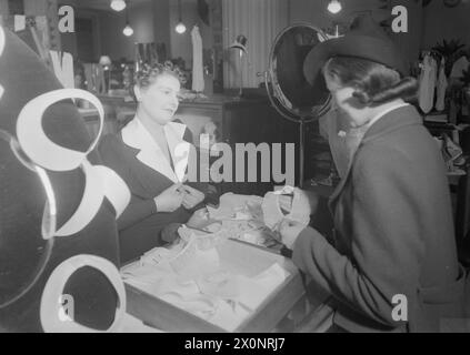 Im Jahr 1940 half ein Vertriebsmitarbeiter bei Selfridge's, London, einem Kunden bei der Auswahl von Verdunkelungsringen, die für Sichtbarkeit während der Kriegszeiten konzipiert wurden. Stockfoto