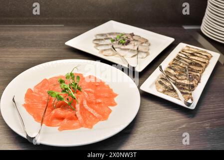 Teller mit gesalzenen Lachsscheiben auf dem Hintergrund von Fischgerichten Stockfoto