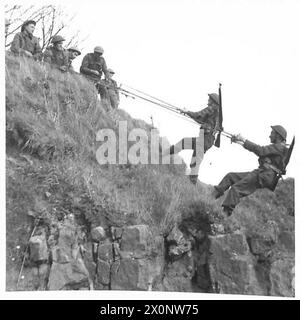 Fotografisches negativ, das die Mitglieder der Hauswache zeigt, die ein Steinbruchgesicht paarweise mit Umschaltseilen skalieren. Stockfoto
