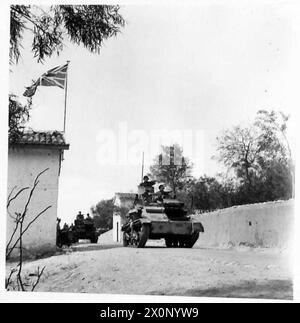 FOTOS, DIE IN ZYPERN GEMACHT WURDEN - Ein leichter Tank, der an einem Cottage vorbeifährt, der den Union Jack fliegt, während er auf einer Reise durch das Land unterwegs ist. Fotografisches negativ, britische Armee Stockfoto