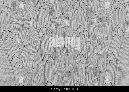 Struktur und Muster eines gestrickten grauen Wollpullovers. Hintergrund von warmem, handgefertigtem Wollgewebe. Stockfoto