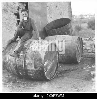 ITALIEN: 8. ARMYFRONT-DORF - Obwohl diese Fässer voller Wein sind, zieht dieser Mann den Liebling der Soldaten vor - Tee! Fotografisches negativ, britische Armee Stockfoto