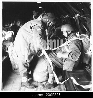 Das Foto zeigt die Ausrüstung, die während der letzten Phasen einer Luftübung an Fallschirmschirmen angebracht wird. Das Bild dokumentiert die Truppenvorbereitung, die Fallschirmplatzierung und die operative Schulung des Flugpersonals. Stockfoto