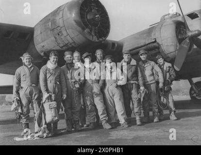 Bomberbesatzung der 91. Bombengruppe steht unter dem beschädigten Triebwerk der B-17 „Wheel and Deal“, Serie 41-24511, nach dem Tageslichtüberfall auf Wilhelmshaven, Deutschland, 22. März 1943. Stockfoto