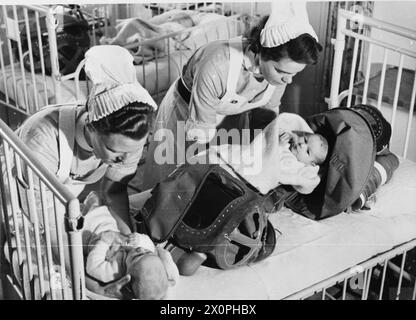 GASBOHRUNG IN Einem LONDONER KRANKENHAUS: GASMASKEN FÜR BABYS WERDEN GETESTET, ENGLAND, 1940 - Krankenschwestern entfernen Babys aus ihren Gasatemgeräten nach einer Gasbohrung in einem Londoner Krankenhaus, 1940 Stockfoto