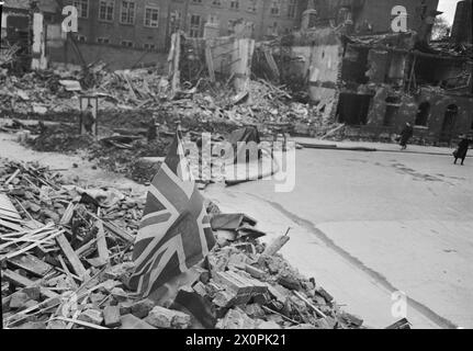 LONDON ZEIGT DIE FLAGGE: DAS LEBEN GEHT WEITER IN KRIEGSZEITEN LONDON, ENGLAND, 1940 - Eine Union Flag sitzt stolz zwischen den Trümmern in einer bombenbeschädigten Londoner Straße, nach einem Luftangriff Stockfoto