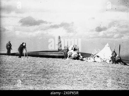 DIE SCHLACHT VON GROSSBRITANNIEN 1940: ZERSTÖRTE DEUTSCHE FLUGZEUGE UND SCHÄDEN – Soldaten, die das brennende Wrack eines Heinkel He 111P-2 von 1(F)ob.d.l, Werks Nr 1594 bewachen, stürzten am 22. Februar 1940 um 30 Uhr in East Coldingham nahe St Abbs Head in Berwickshire ab. Das Flugzeug wurde von Squadron Leader A D Farquhar in einem Spitfire der No 602 Squadron und Pilot Officer G V Proudman in einem Kanonenfeuer der No 65 Squadron abgefangen. Der Heinkel wurde anschließend von seiner Besatzung zerstört. Die vierköpfige Besatzung wurde gefangen genommen, einer von ihnen wurde verletzt Stockfoto