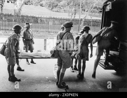 DER FERNE OSTEN: SINGAPUR, MALAYA UND HONGKONG 1939-1945 – der japanische Feldzug und Sieg 8. Dezember 1941 – 15. Februar 1942: Chinesische Bahrenträger laden unter Aufsicht britischer und australischer Offiziere einen in Malaya verwundeten Soldaten in einen Krankenwagen Stockfoto