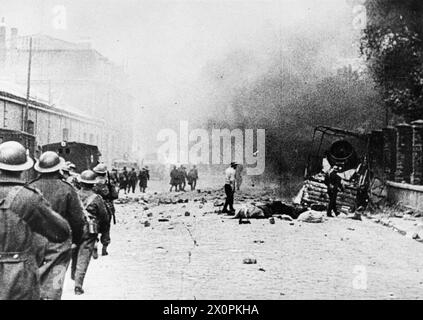 DIE BRITISCHE ARMEE IN FRANKREICH, 1940 - Truppen durchqueren eine Straße in Dünkirchen unter deutscher Beschuss, als sie sich an die Strände zur Evakuierung zurückziehen, am 1. Juni 1940. Auf der rechten Seite haben die französischen Feuerwehrleute einen brennenden LKW Stockfoto