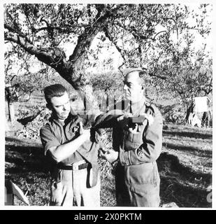 ITALIEN: ACHTE ARMEE: NEUFUNDLAND-SCHÜTZE IN ITALIEN - RQM W. Venters of Corner Brooks, Neufundland, hilft GNR. C. House of Grand Falls, Neufundland, um eine neue Kampfkleid-Bluse auszuwählen. Fotografisches negativ, britische Armee Stockfoto