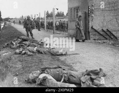 DER HOLOCAUST, 1941-1945 – Leichen einiger ehemaliger SS-Wachen liegen auf einem Graben um das Konzentrationslager Dachau, während Truppen der 7. US-Armee das Gebiet patrouillieren und befreite Gefangene in der elektrifizierten Stacheldrahtzauge, Ende April 1945 US-Armee, kontrollieren Stockfoto