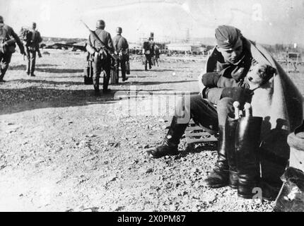 DIE DEUTSCHE INVASION IN NORWEGEN, 1940 - Ein deutscher Soldat wiegt seinen Hund, während andere Truppen Vorräte von Flugzeugen auf einem Flugplatz in Norwegen transportieren, 10. April 1940 Deutsche Armee Stockfoto