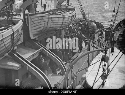 KREUZKANALDAMPFER JETZT ERHOLUNGSSCHIFF FÜR SEELEUTE. JUNI 1943, SCAPA FLOW. DER KREUZKANALDAMPFER AUTOCARRIER, DER FRÜHER URLAUBSWAGEN VON UND NACH FRANKREICH TRANSPORTIERTE, IST HEUTE EIN ERHOLUNGSSCHIFF FÜR DIE BESATZUNGEN DER VIELEN HILFSKRAFTSCHIFFE DER HEIMATFLOTTE, DIE SICH UM DEN SERVICE DER ROYAL NAVY KÜMMERN. ES IST DAS ERSTE UND EINZIGE SEINER ART, UND FÜR TAUSENDE VON MÄNNERN BEDEUTET ES EINMAL PRO WOCHE BIER UND "FLICKS". - Männer kaufen Waren aus der NAAFI-Kantine an Bord, bevor sie einen Drifter zu ihrem Schiff holen Stockfoto