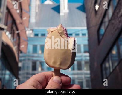 Abgeschnittene Hand, die Eis am Gebäude hält Stockfoto